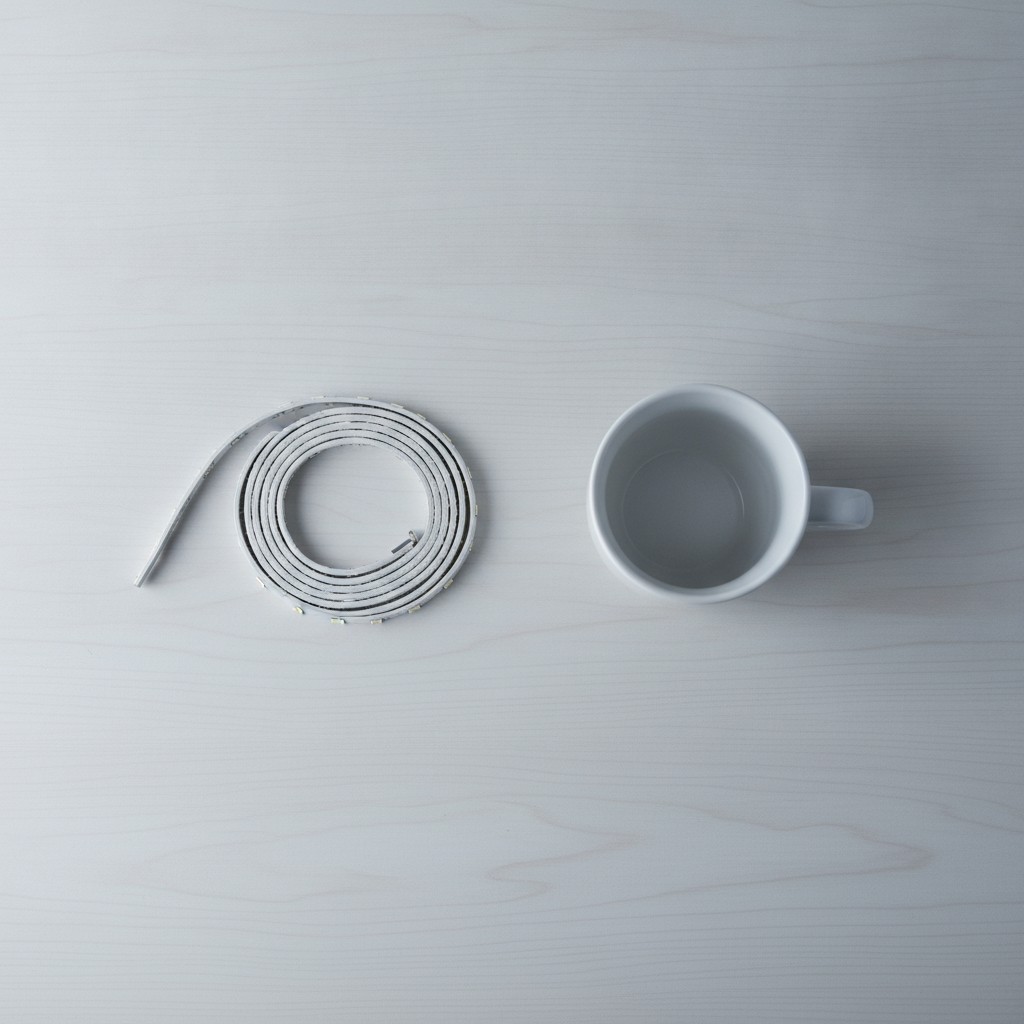 Rouleau de ruban lumineux comparé à un mug posé sur une table